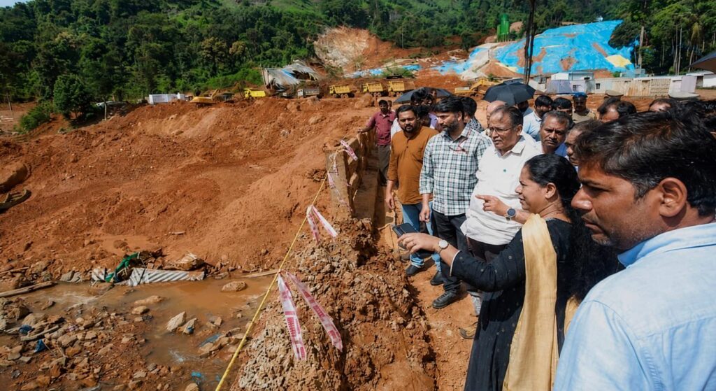 A large mound of excavated soil near a rehabilitation township construction site overlooking residential houses in Kalpetta, highlighting potential landslide risks to nearby families.